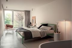 Bett mit grünem Rahmen im hell gestalteten Schlafzimmer