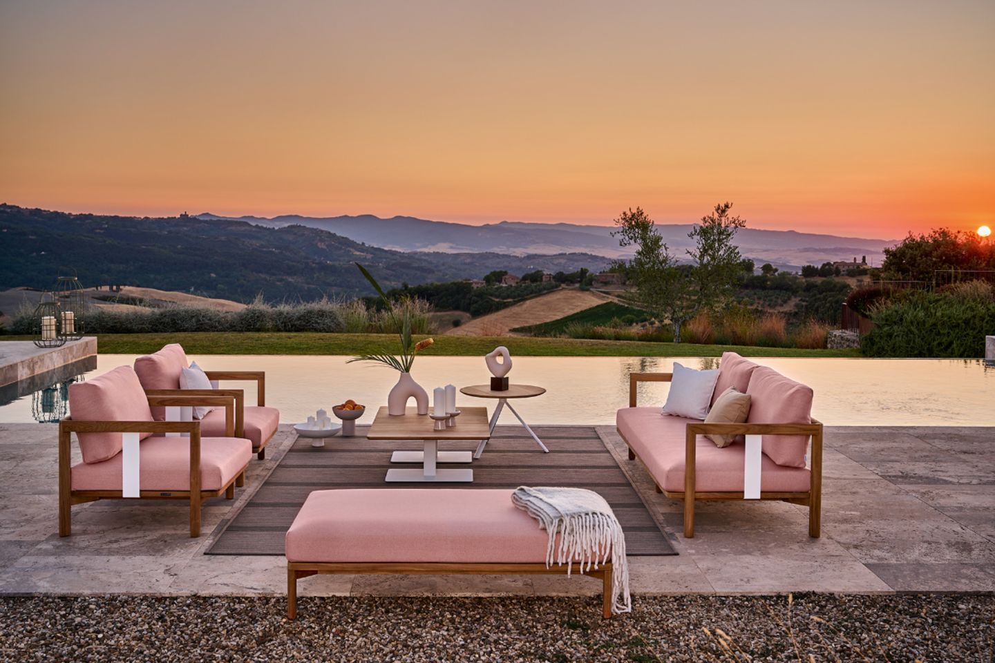 Rosafarbene Polstermöbel auf Terrasse mit Hügellandschaft im Sonnenuntergang