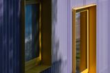 Violette Hausfassade aus Wellplatten mit gelben Fensterrahmen