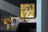 Küchentresen in Blau mit Blumenstrauß und gelbes Alu-Fenster in die Natur