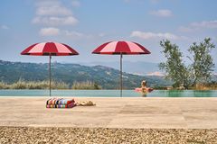 Zwei rot und rosa gestreifte Sonnenschirme neben einem Pool