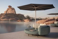 Lounge-Liege mit integriertem Sonnenschirm vor einer Seelandschaft