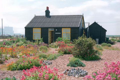Schwarzes Haus inmitten von Blumen in einer kargen Landschaft