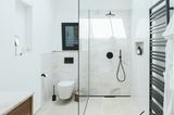 Badezimmer mit Wänden und Waschtisch aus Marmor und schwarzen Armaturen