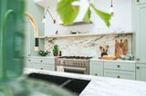 Salbeifarbene Küche mit Industrieherd und Küchenrückwand aus Marmor