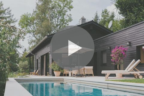 Schwarzes Holzhaus mi Pool umgeben von Bäumen