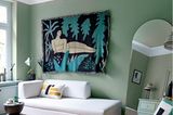 Helles Sofa in Gästezimmer mit silberfarbenen Wänden und Decke, Wandteppich und Spiegel