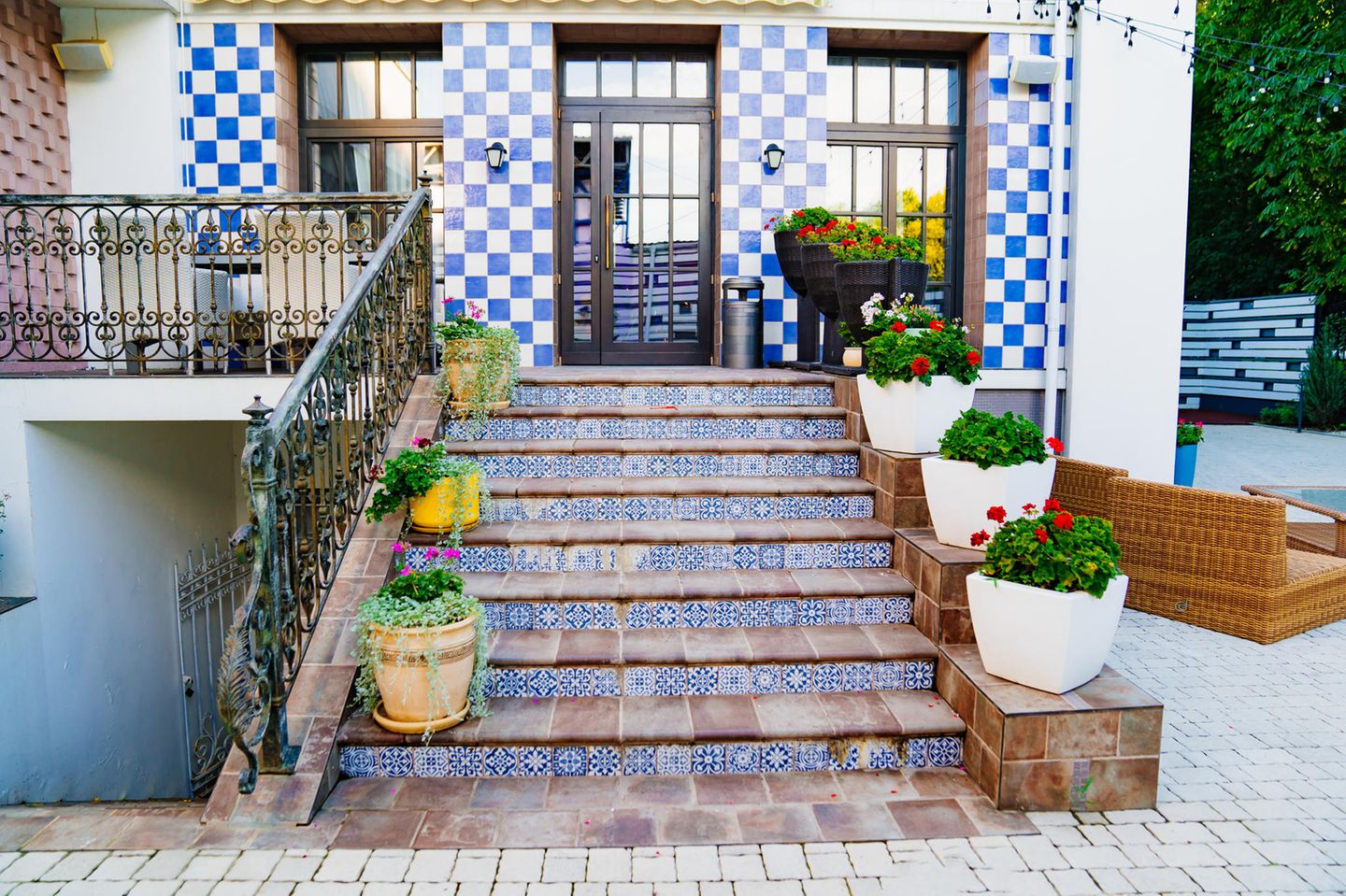 Eine alte Steintreppe mit blau-weißen Fließen mit Muster und eine Hausfassade mit Schachbrettmuster