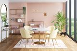 Ein runder Esstisch mit goldenem Fuß und vier hellgelbe Stühle stehen vor einer rosa Wand