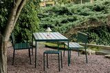 Gartentisch und Sitzmöbel aus Stahl versteckt hinter einer Hecke