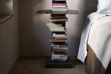Bücher stapeln sich auf einem vertikalen Regal mit Ablagefläche.
