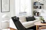 Wohnzimmer mit starken Kontrasten aus Schwarz und Weiß un einem Holztisch vor dem weißen Sofa
