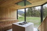 Eine Sauna mit großem Ofen und Glasfront mit Sicht in den Garten