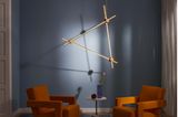 Dreieckige Wandleuchte aus Messing vor einer blauen Wand
