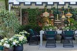 Bunte Stoffleuchten über Esstisch in Gartenzelt auf Terrasse