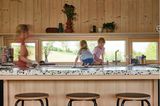 Offene Küche mit Kindern auf der Arbeitsfläche und Ausblick ins Grüne