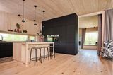 Küche und Wohn-Essbereich in einem Holzhaus mit schwarzer Wandscheibe und Tresen