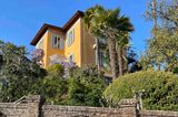 Gelbe Jugendstil Villa umgeben von Palmen und Azaleen