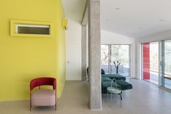 Offener Wohnbereich mit bunten Polstermöbeln auf Terrazzoboden und gelber Wand