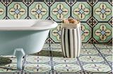 Bad mit Badewanne und floraler Ornamentik durch Zementfliesen an Wand und auf dem Boden