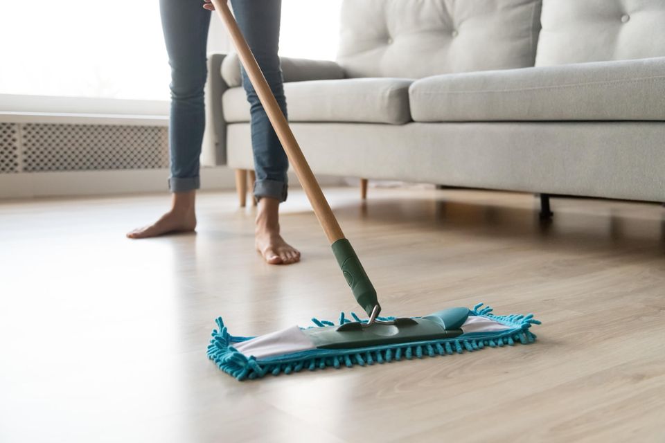 Eine Frau wischt im Wohnzimmer einen Laminatfußboden