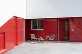 Betonterrasse mit Sitzgruppe vor Sockel aus rotglänzenden Fliesen