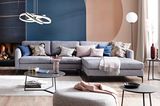 Graues Sofa vor Tapete mit grafischen Elementen