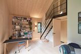 Holzverkleidetes Wohnzimmer mit Stahltreppe zum Schlafraum