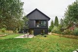 Schwarzes Holzhaus mit Garten und heller Holzterrasse