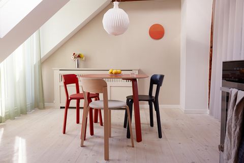 Esszimmertisch und Stühle in Rot und Blau unter einer Dachschräge und einer Papierleuchte