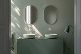 Badezimmer mit Möbeln und Wänden in Salbeigrün mit weißen Aufsatz-Waschbecken