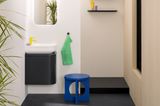 Kleines Badezimmer mit schwarzem Unterschrank, gelbem Wasserhahn und bunten Accessoires