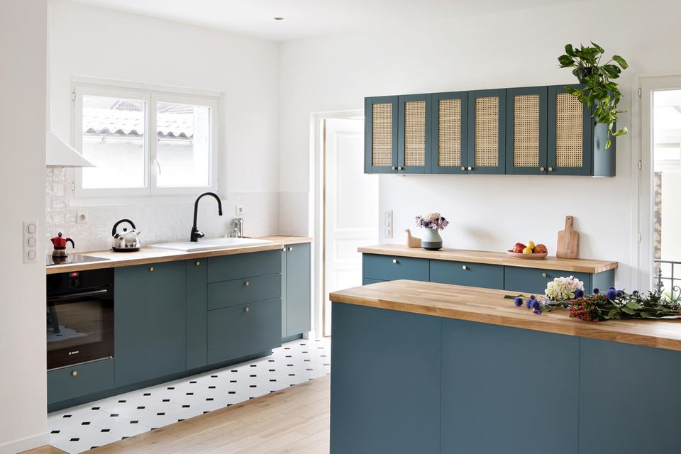 Blaue Küche mit Rattan und Parkettboden sowie schwarz-weißen Fliesen