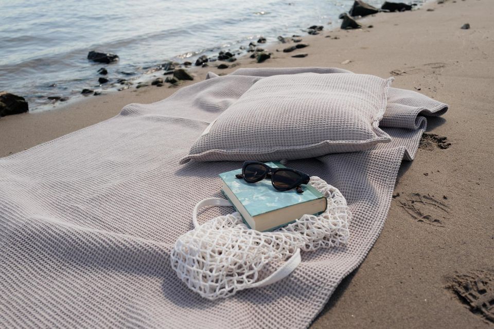 Handtuch und Kissen in Taupe am Strand