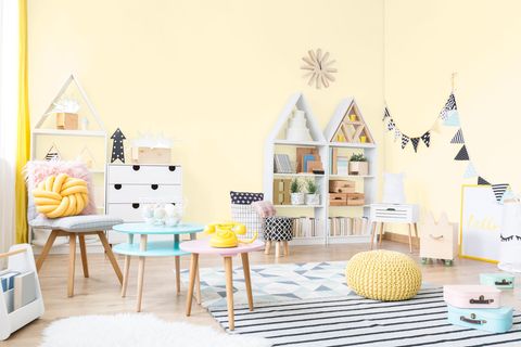 Kinderzimmer mit verschiedenen bunten Möbeln, gelber Wandfarbe und einer Girlande an der Wand