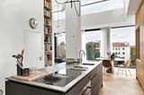Schwarze Küche und runder Esstisch mit Blick auf Hausdächer