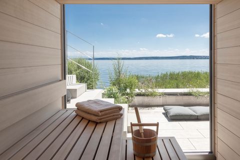 Sauna von innen mit Blick durch Panoramafenster auf Terrasse und See