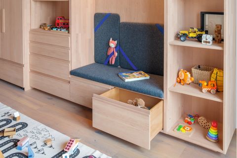 Eingebaute Sitznische in der Kinderzimmer-Regalwand aus hellem Erlenholz mit Schubladen, Türen und offenen Regalen