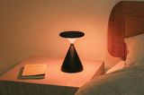 Smarte, mobile Leuchte mit "Sunset Dimming" auf einem Nachttisch neben einem Bett