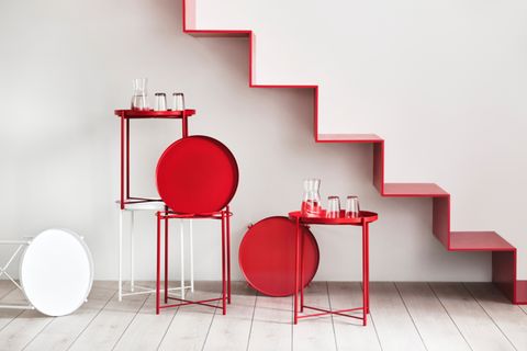Gestapelte runde Beistelltische in Rot und Weiß unter roter Treppe