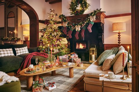 Weihnachtliches Wohnzimmer mit einem Kamin, gedeckten Couchtisch und Geschenken