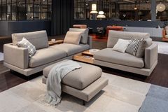 Modulares Sofa in Grau auf einem beigen Teppich mit Papierleuchten im Hintergrund