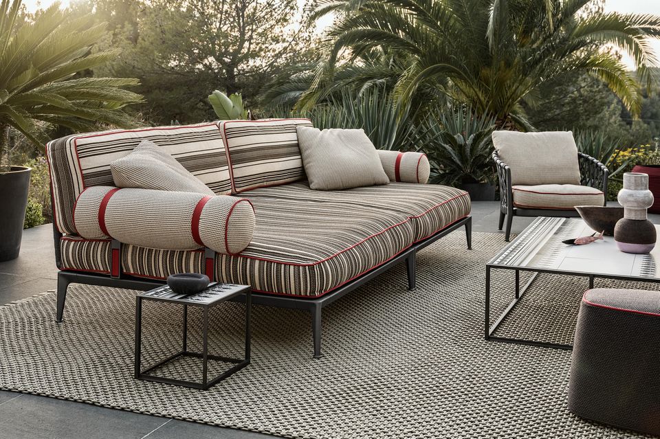 Ein Outdoor-Sofa auf einem Outdoor-Teppich von Palmen umgeben