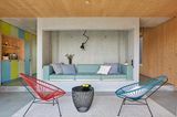 Raum mit beton- und holzwänden, einem einbausofa, Acapulco Stühlen und bunter Küche