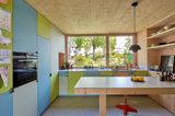 Küche mit grünen und blauen Schränken, großer Holzinsel und Fensterfront
