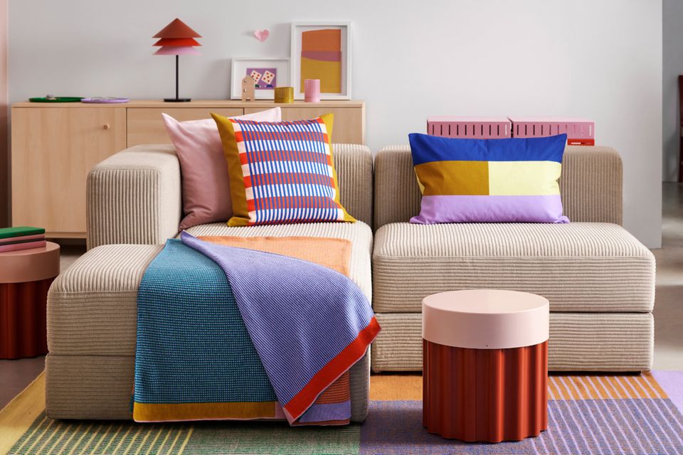 Wohnzimmer mit beigem Sofa und bunten Textilien der Kollektion