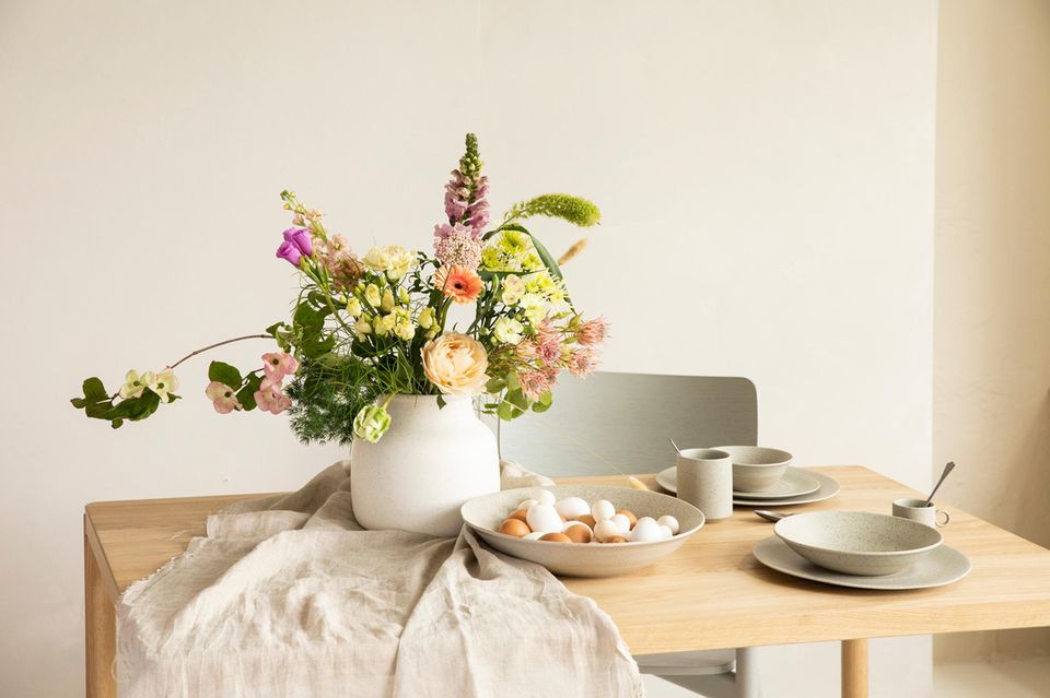 Frühlingshafter Tisch mit Blumenstrauß und Ostereiern