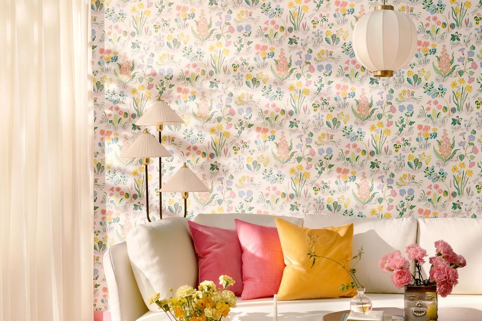 Florale Tapete in Pastellfarben im Wohnzimmer hinter der Couch an der Wand