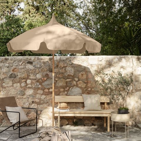 Pagodenschirm in Beige vor Steinmauer auf mediterraner Terrasse